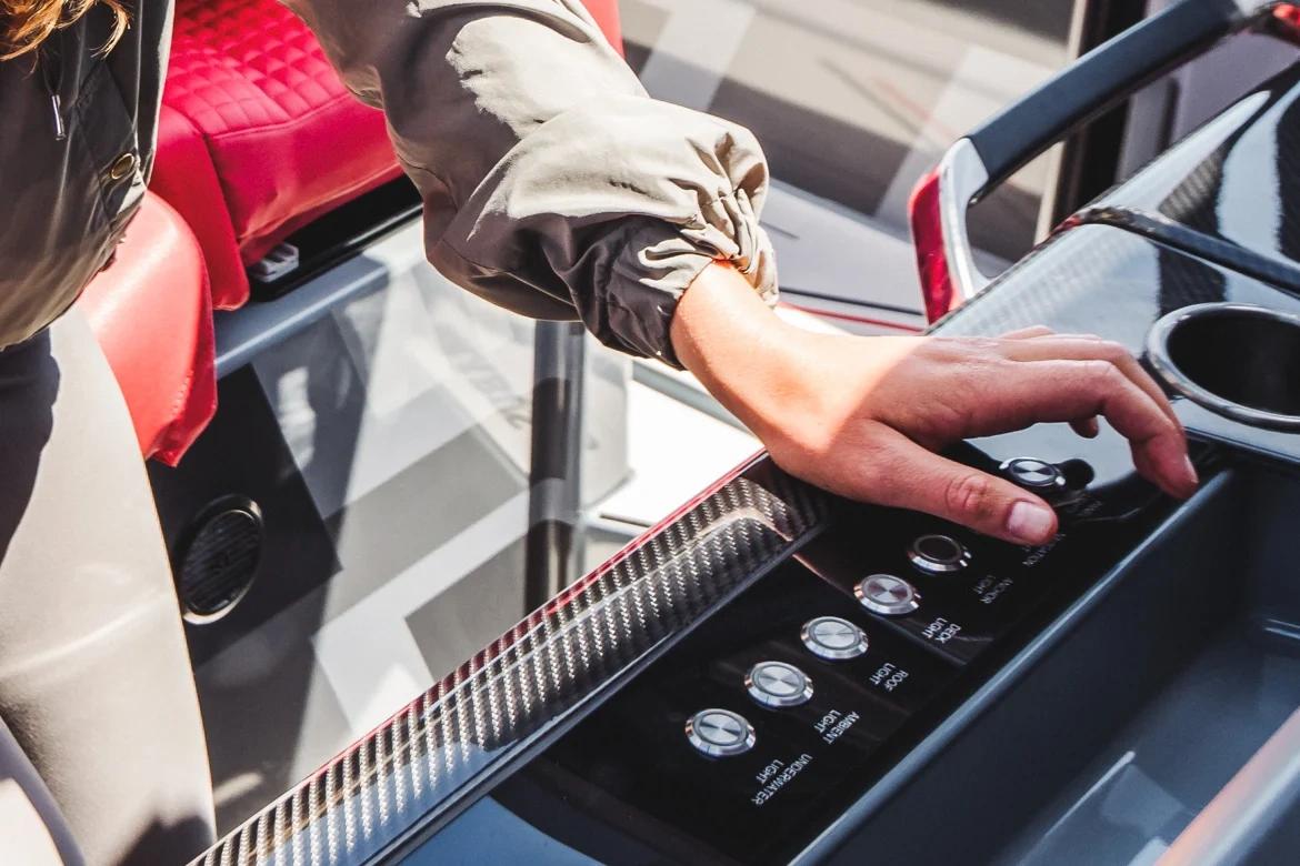 Personne ajustant des commandes de bateau Brabus Marine avec gants blancs dans un cockpit luxueux