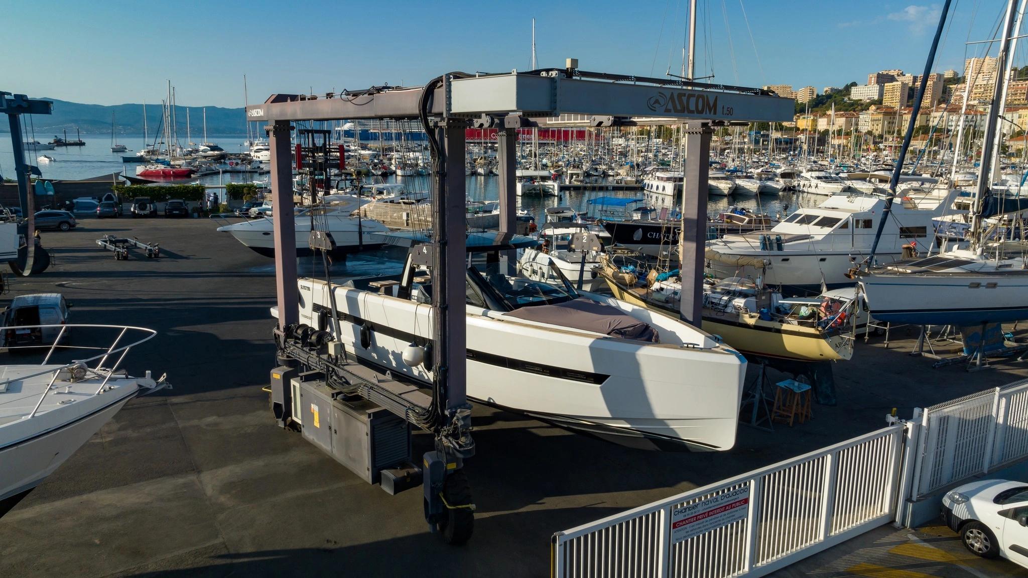 Bateau blanc en chantier naval avec grue de manutention dans un port méditerranéen