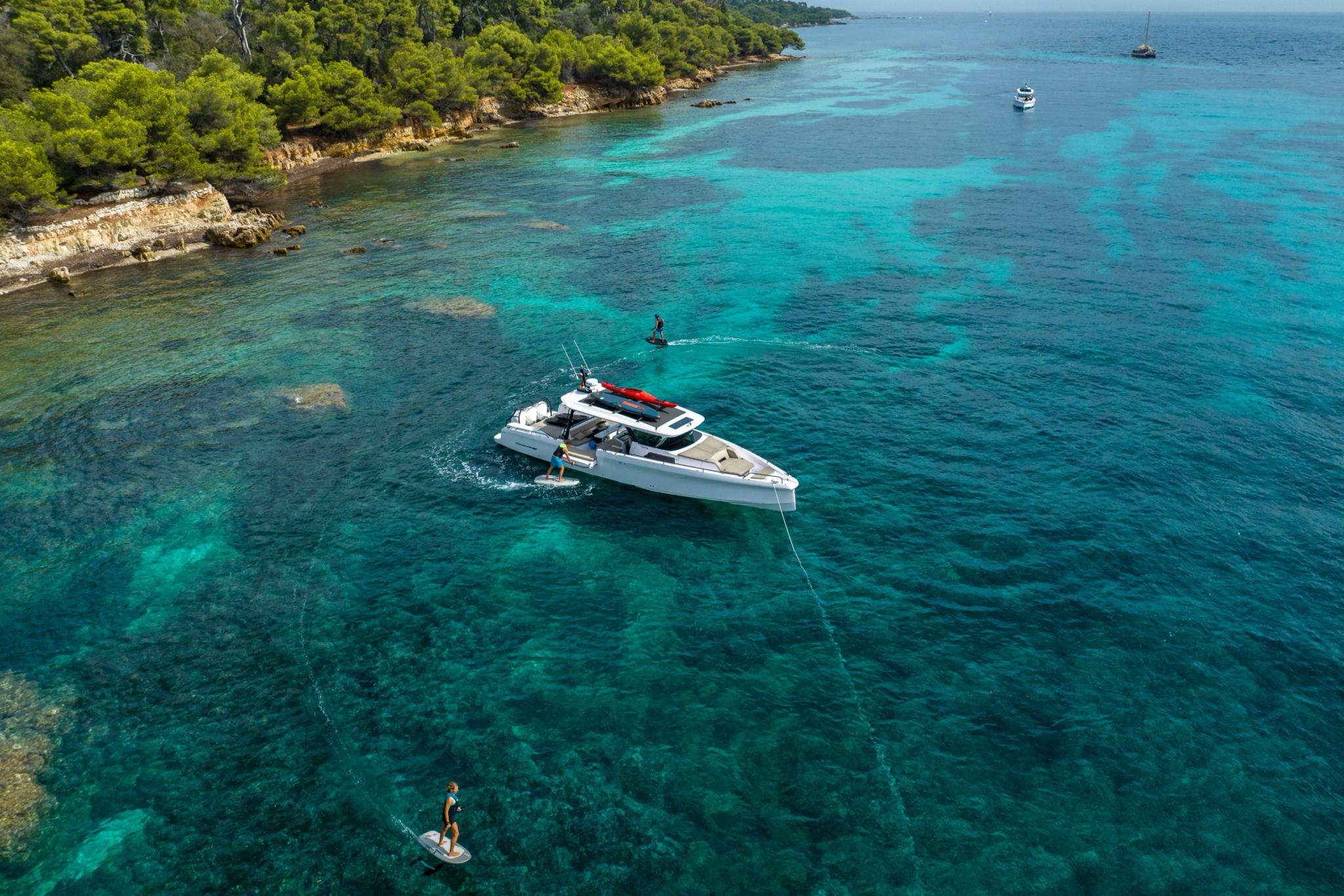 Bateau Axopar ancré en eau turquoise avec plongeurs et voiliers en Méditerranée