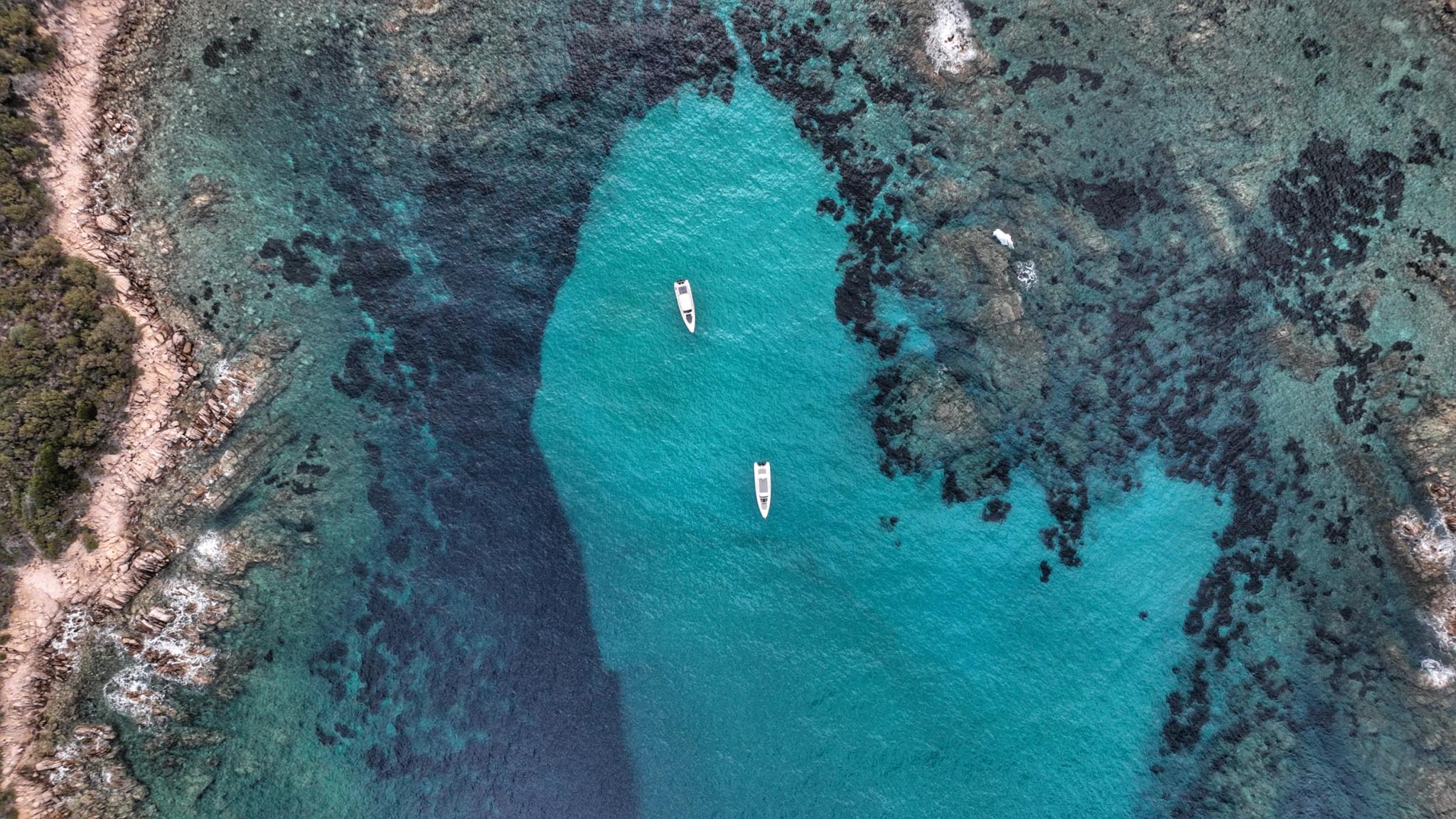 Vue aérienne d'une crique turquoise avec deux bateaux en location côtier méditerranéen