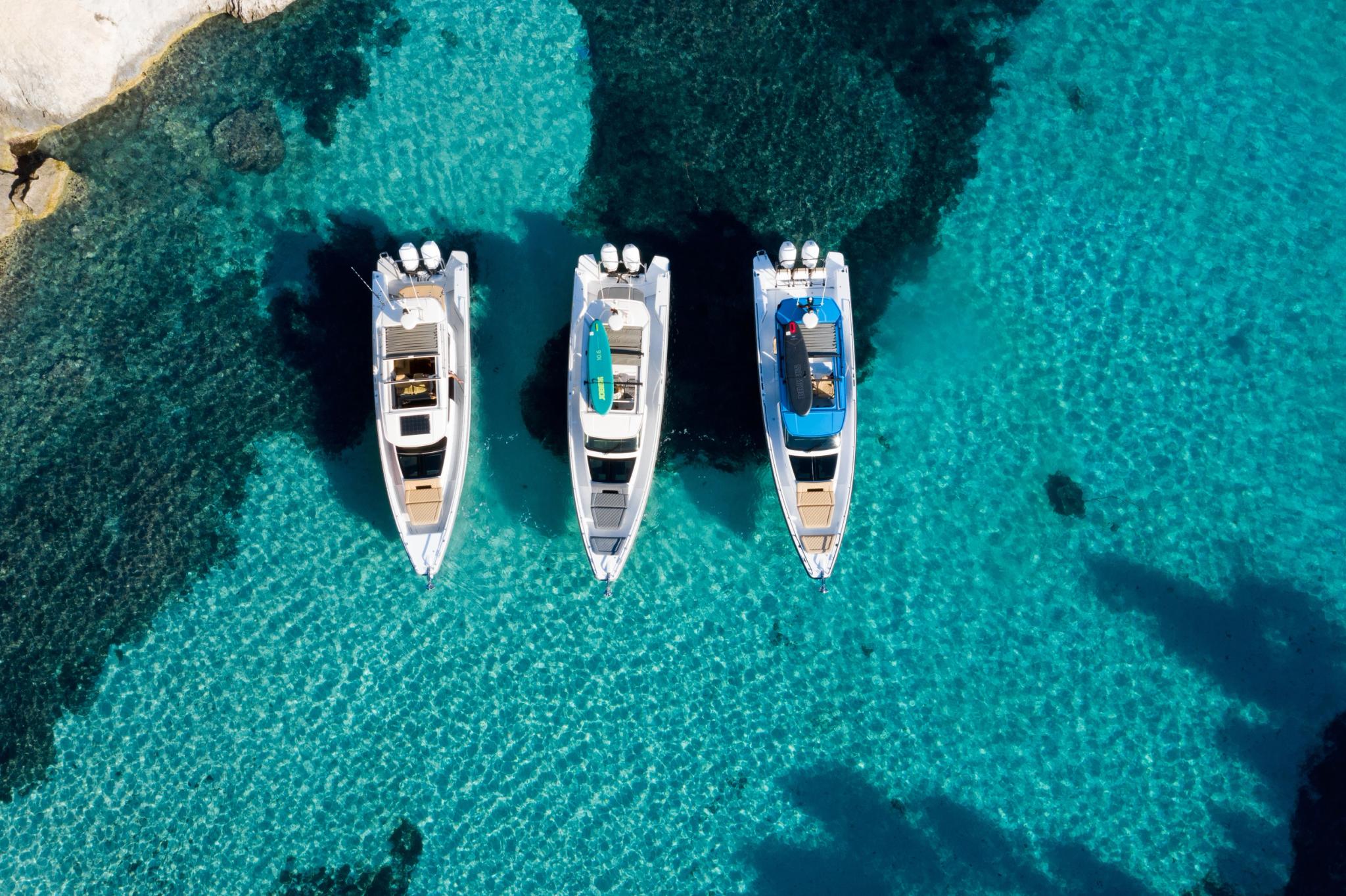 Trois bateaux d'occasion amarrés en mer turquoise vue aérienne