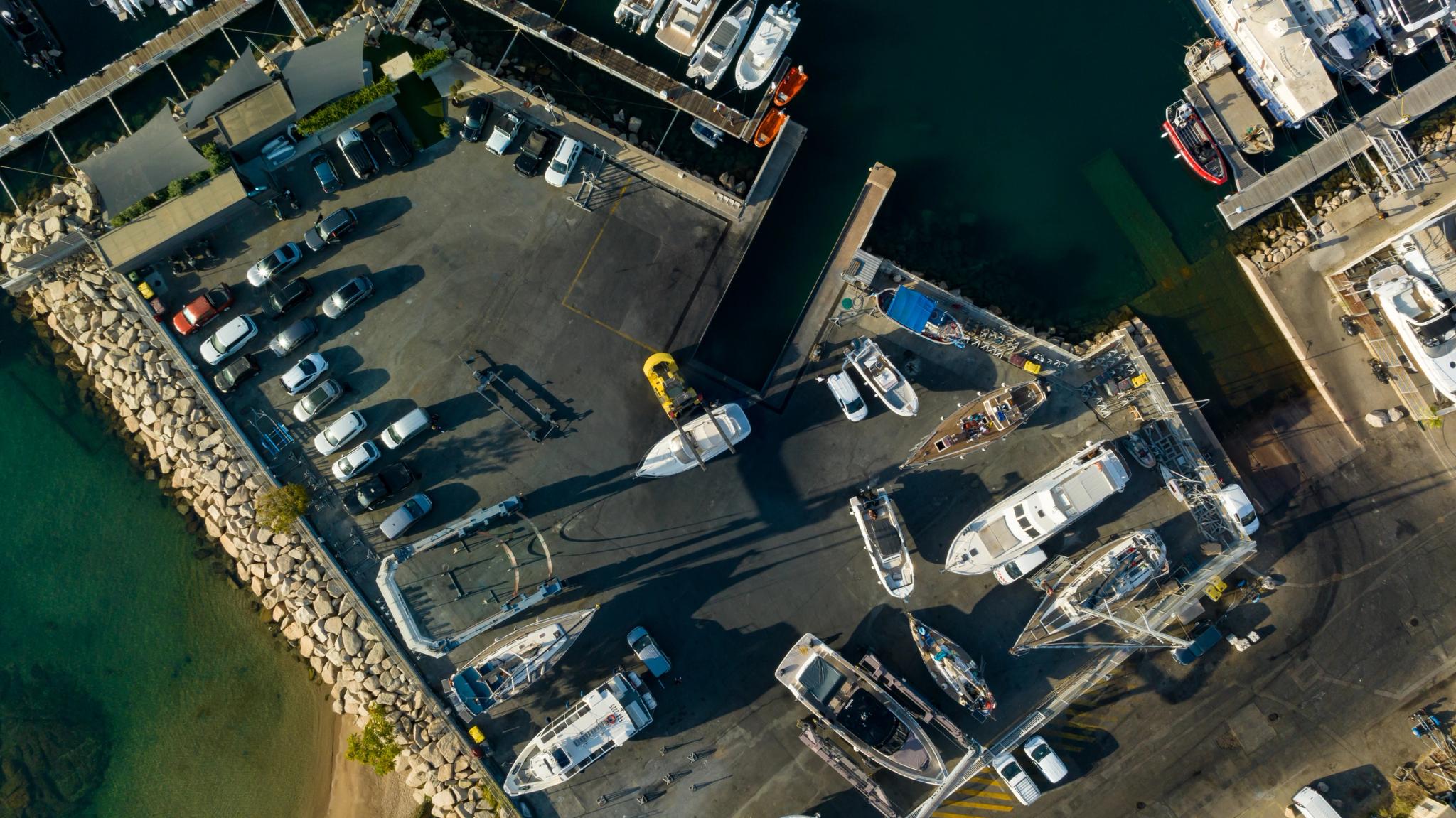 Vue aérienne d'un chantier naval côtier avec bateaux et voiliers amarrés