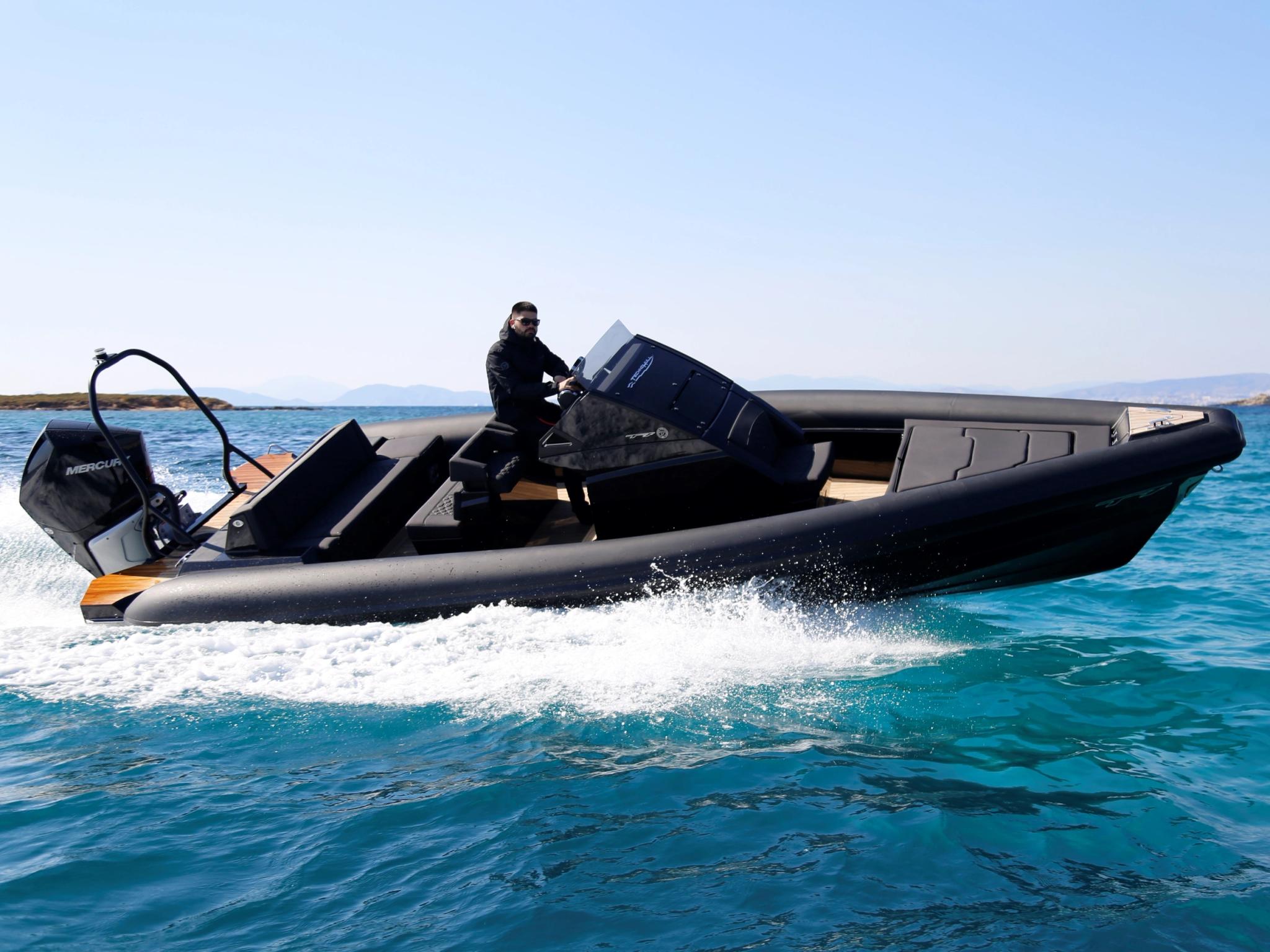 Bateau à moteur Technohull noir naviguant sur une mer turquoise avec un opérateur à bord