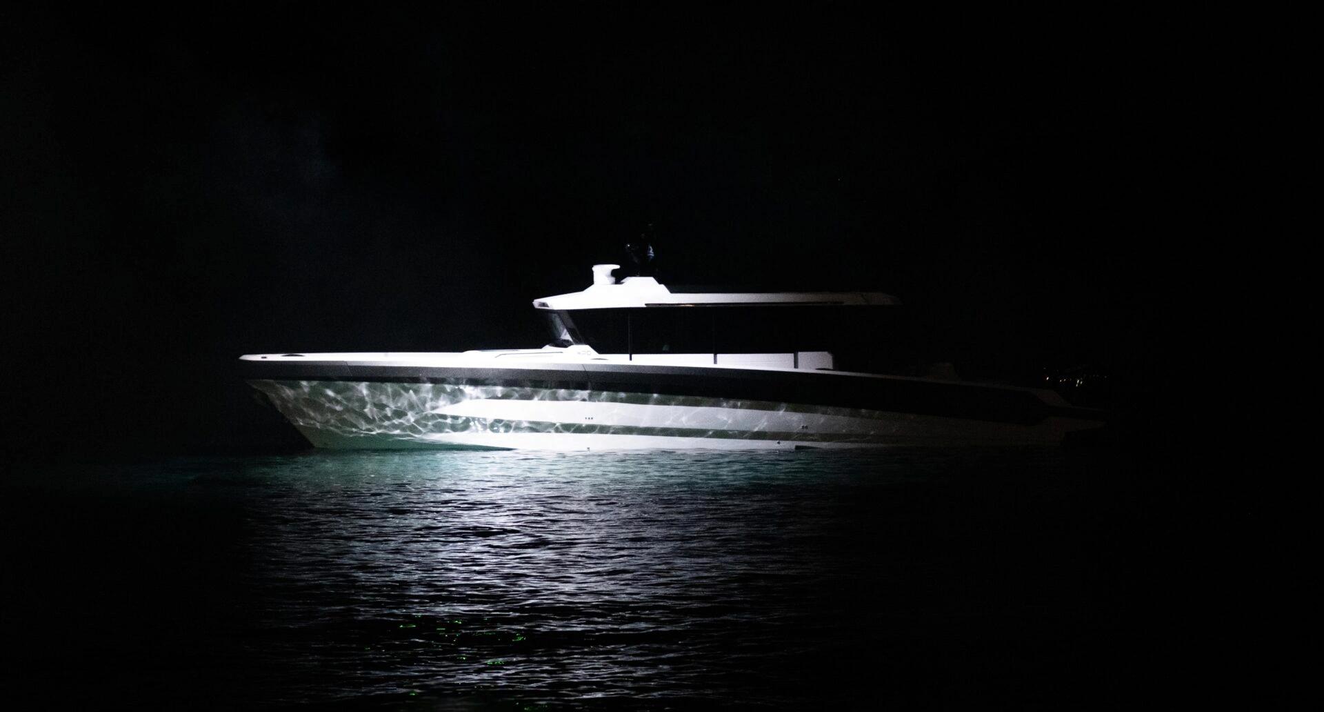 Technohull bateau yacht illuminé de nuit sur l'eau sombre