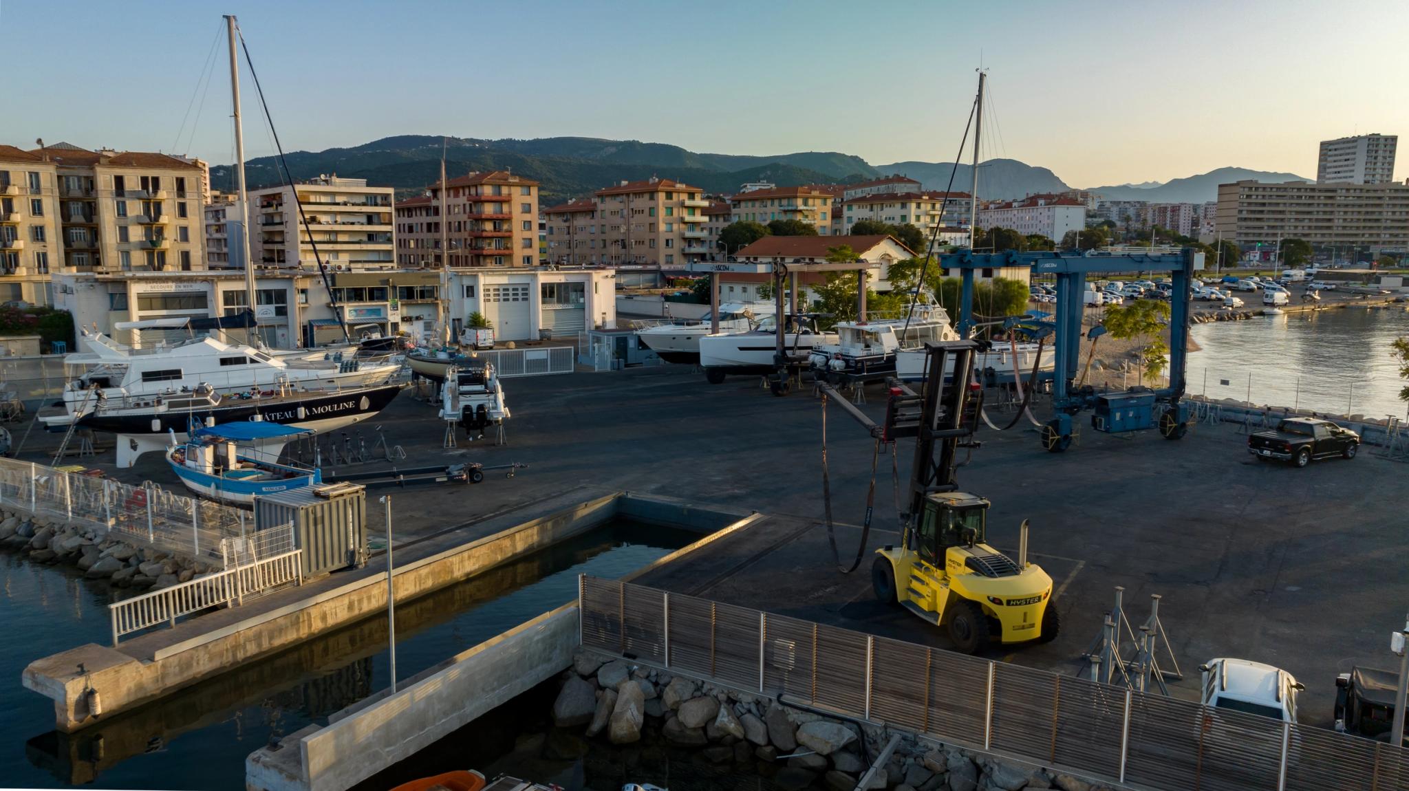 Chantier naval avec bateaux, grues et équipements portuaires en bord de mer