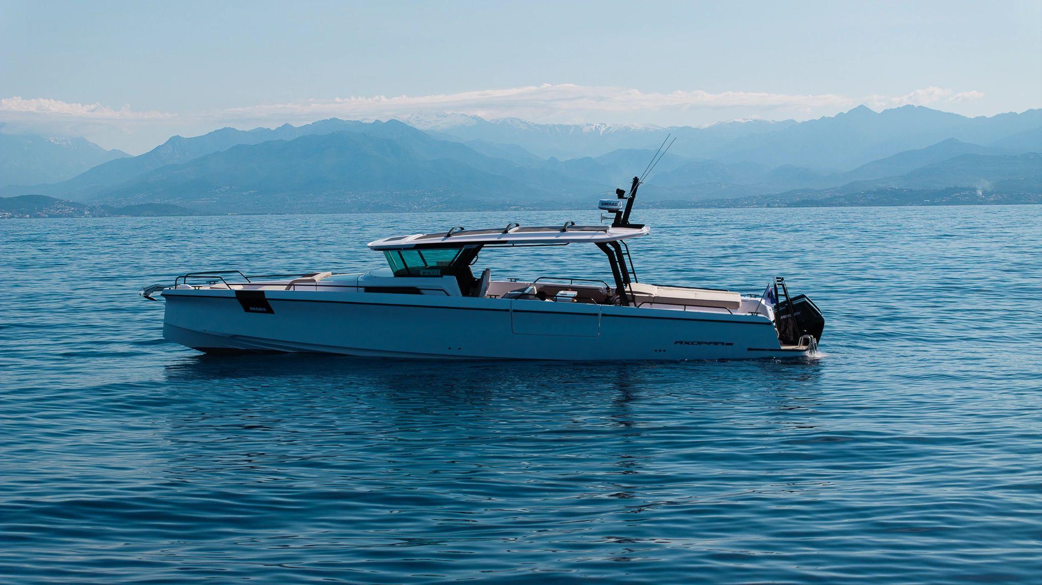 Bateau neuf bleu amarré en méditerranée avec montagnes en arrière-plan